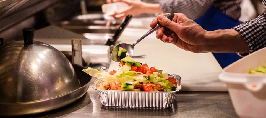 Close up of a chef spooning vegetables onto the plated meal.