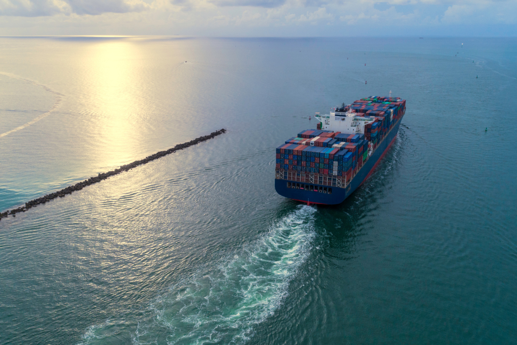 Behind view of a cargo ship moving through the sea.