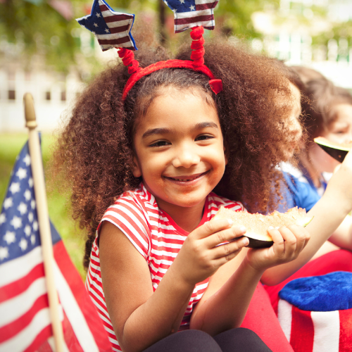 Child holding a slice of watermelon. Dressed in 4th of July attire. 