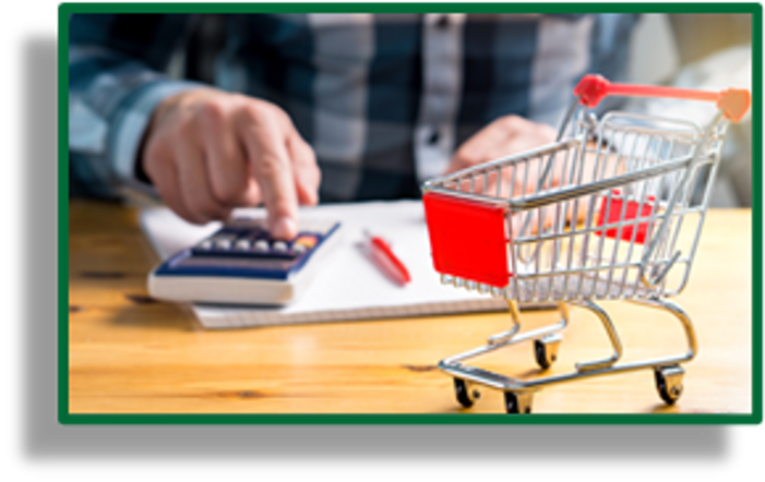 Close up of someone using a calculator and a small shopping cart sitting on the table next to them.